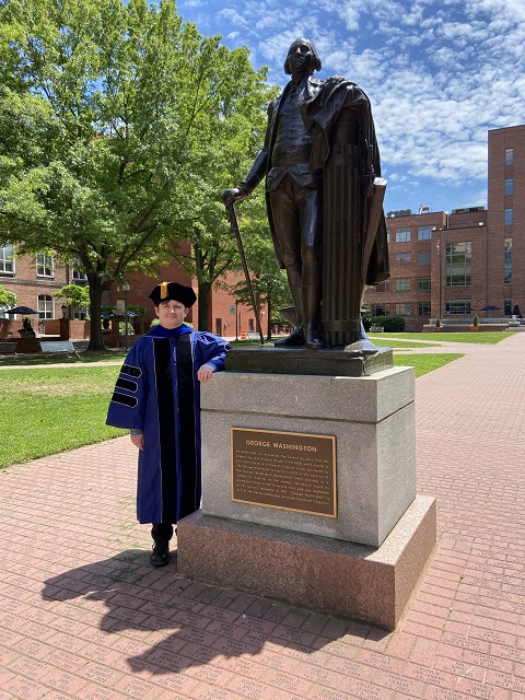 Kieran dressed for graduation with statue