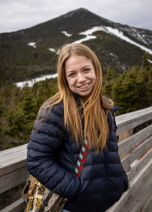A smiling woman standing in front of a snow covered mountain 