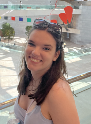 Woman in a blue dress smiling while standing in an art gallery  